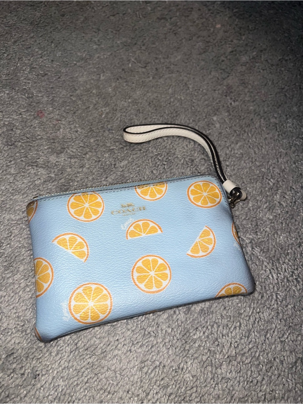 light blue Coach corner zip wristlet featuring orange print